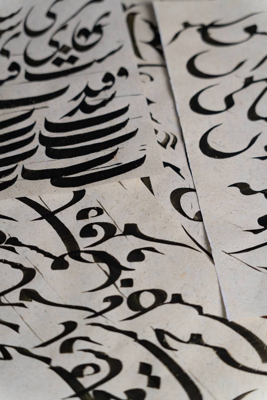 Close view of flowing nastaliq strokes on straw-flecked paper
